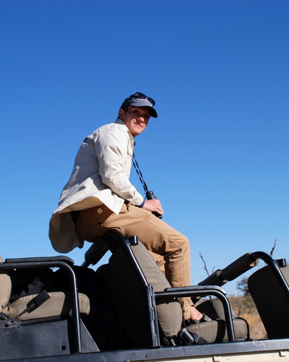 A young traveller scanning the bush from a safari game-drive vehicle